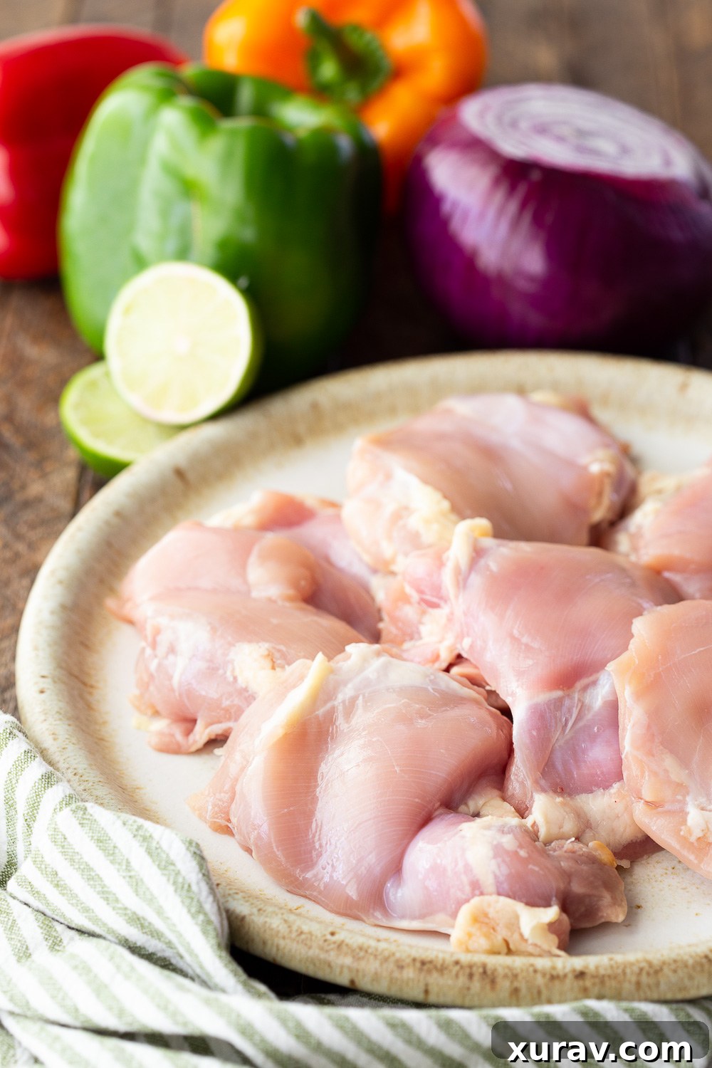 What you need to make chicken fajitas. A vibrant display of fresh chicken thighs, onion, lime, and colorful bell peppers.