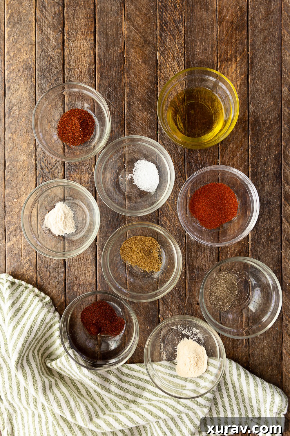 All the spices needed to make chicken fajitas. A collection of chili powder, chipotle powder, smoked paprika, onion powder, garlic powder, black pepper, cumin, and salt.