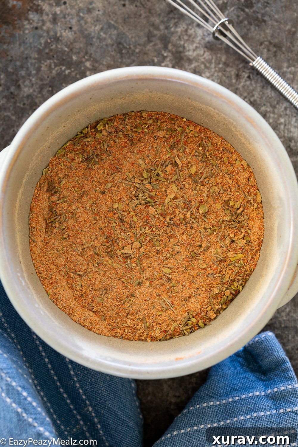 Mixing together a homemade spice blend, with various colorful spices visibly combining in a bowl.