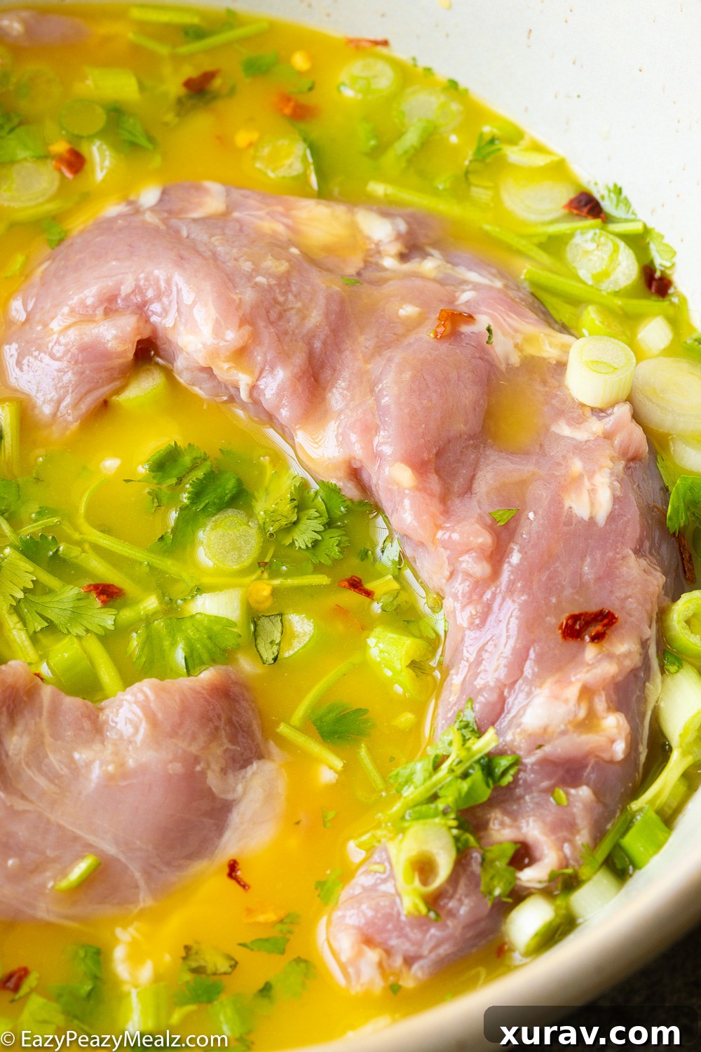 Pork tenderloin marinating in a vibrant citrus mojo sauce in a resealable bag