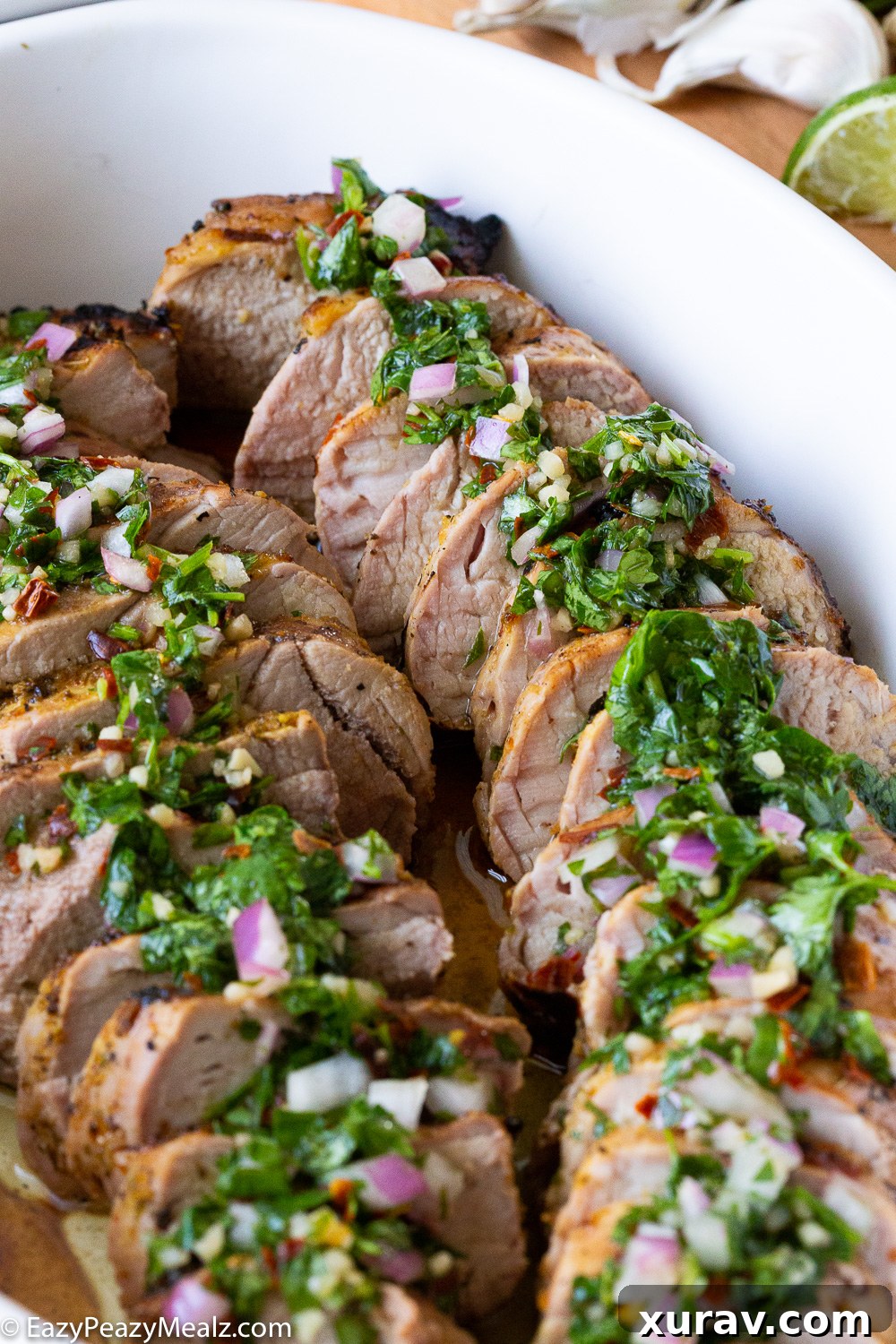 Close-up of perfectly grilled mojo pork tenderloin with a vibrant chimichurri topping