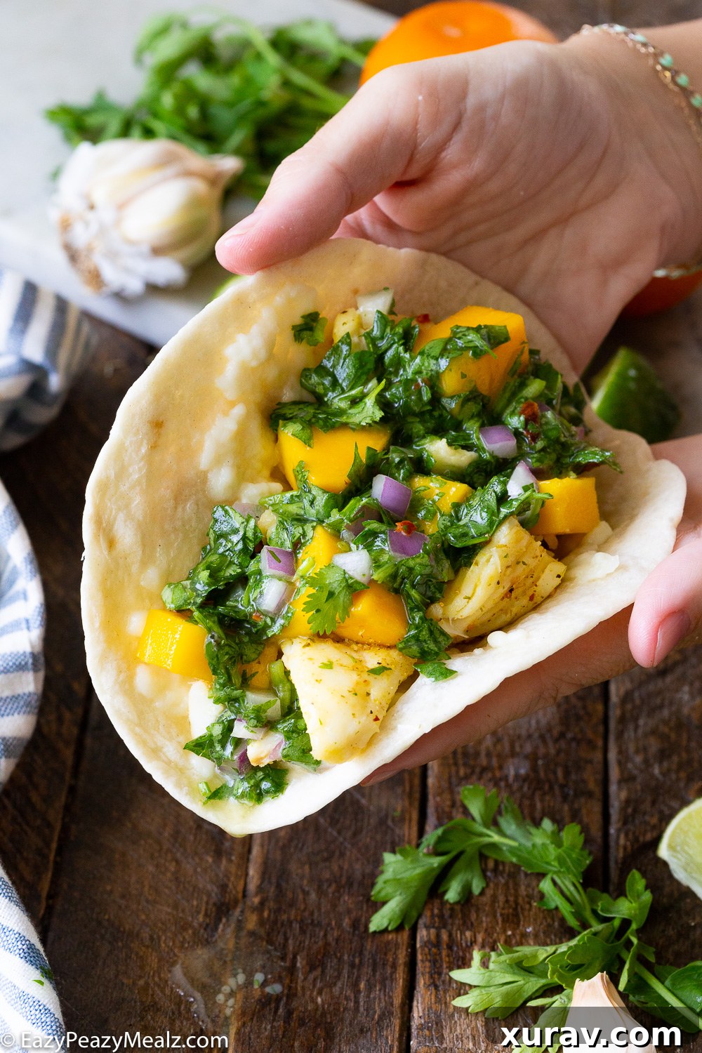 Assembling halibut fish tacos, with a grilled citrus marinated halibut and a mango and chimichurri topping