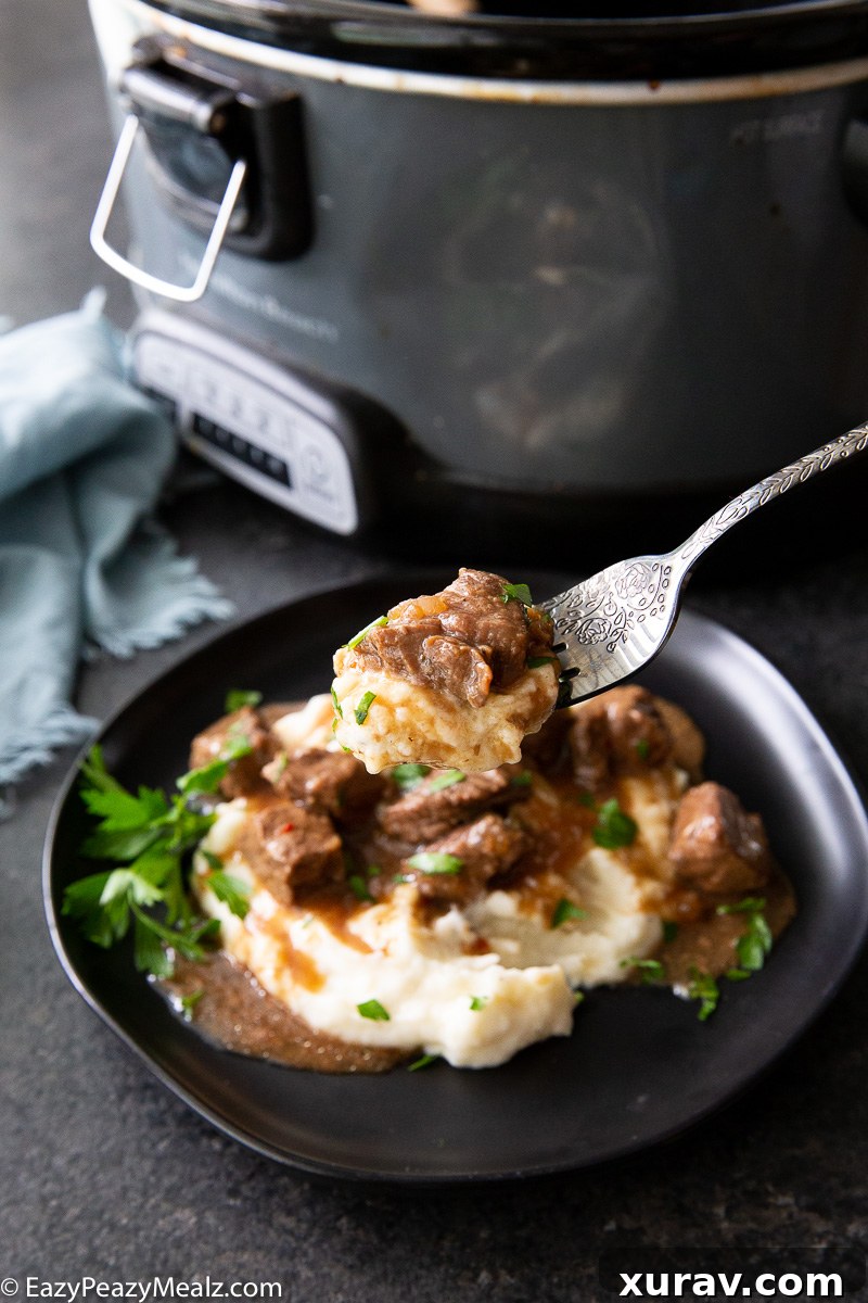 A fork full of slow cooker steak bites and mashed potatoes
