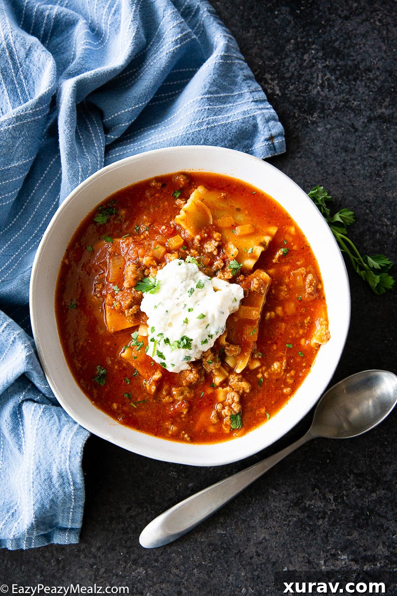 A bowl of Slow Cooker Lasagna Soup, garnished with a creamy ricotta topping and fresh herbs.