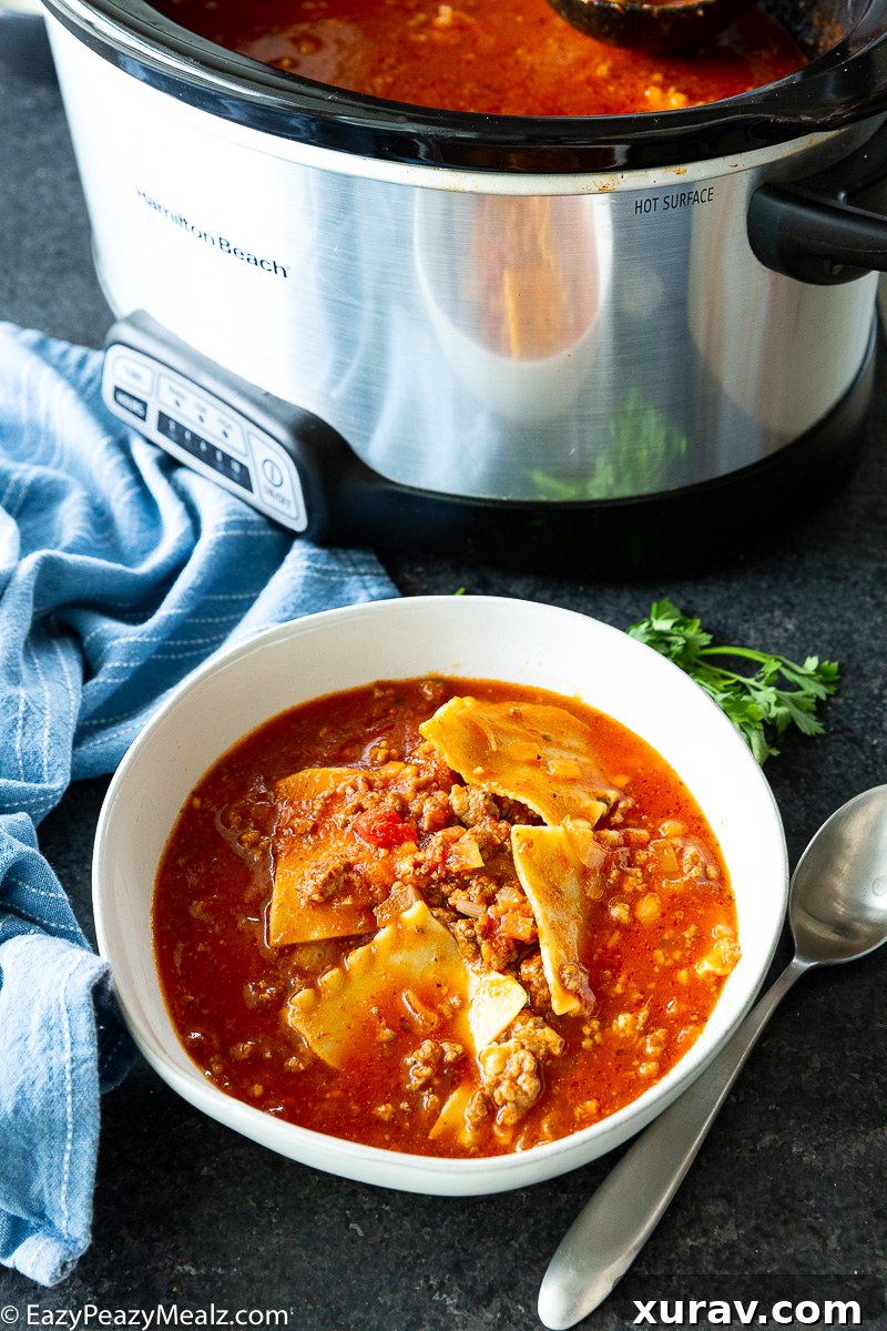A large pot of Slow Cooker Lasagna Soup before the cheese topping has been added, showing the rich red broth and tender noodles.