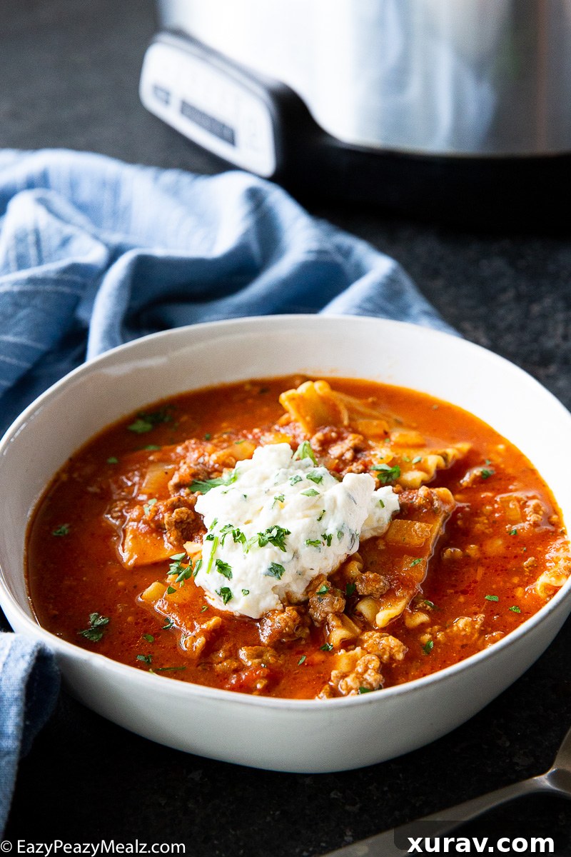 A close-up shot of a steaming bowl of Slow Cooker Lasagna Soup, perfectly garnished with cheese and basil.