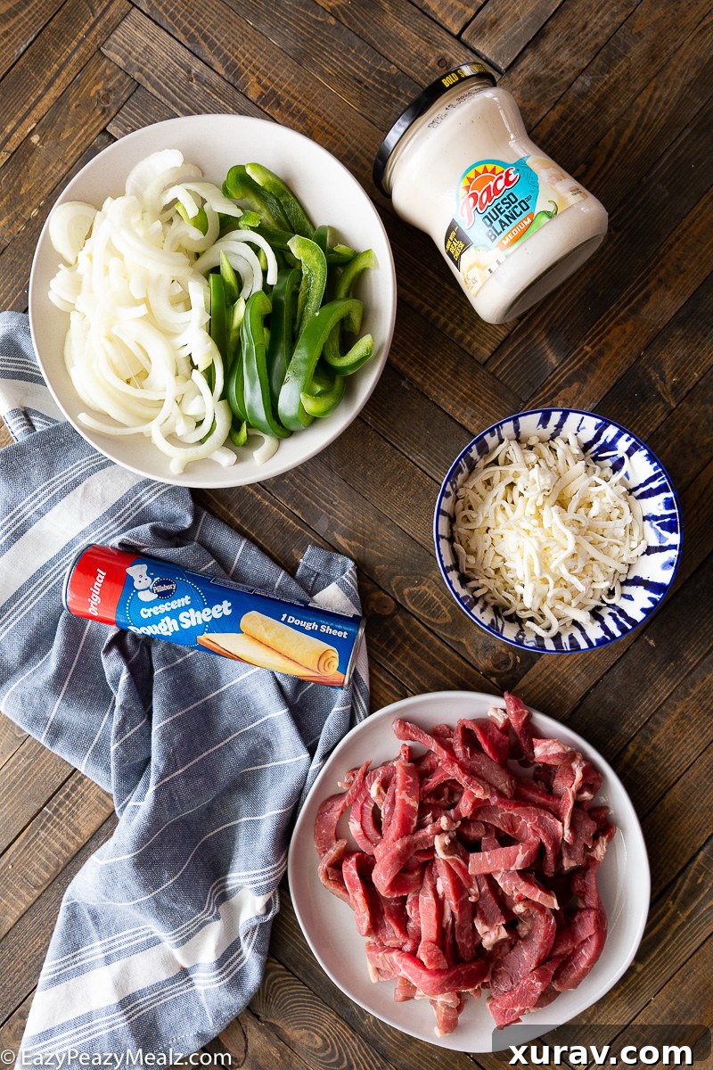 All the fresh ingredients laid out for making the Philly Cheesesteak Bake, including thinly sliced steak, bell peppers, onions, cheeses, and crescent roll dough.