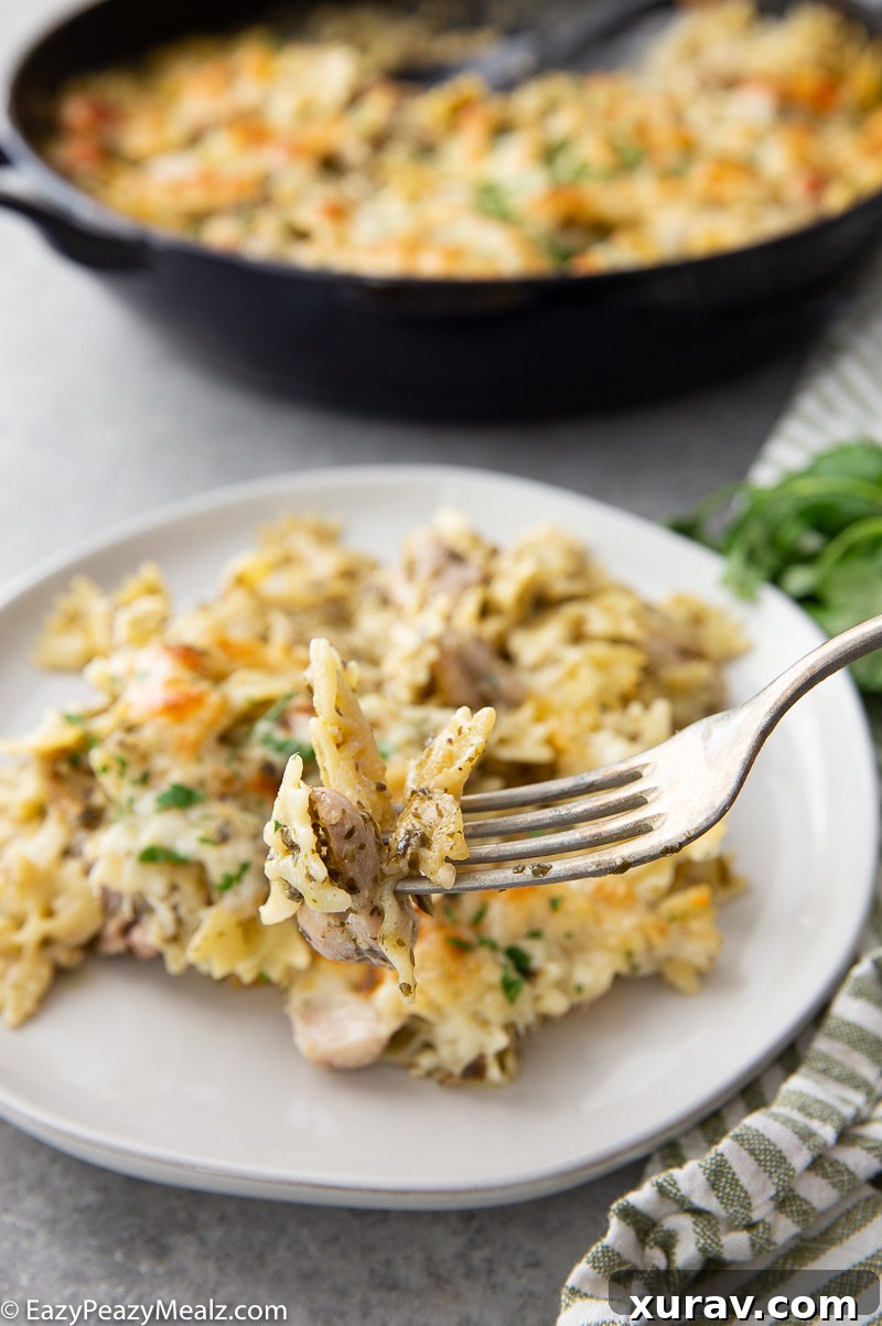 A fork full of pesto chicken pasta bake, showing melted cheese and tender chicken.