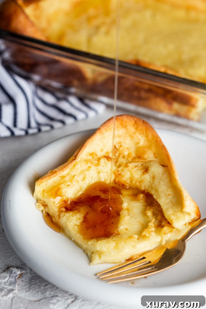German pancakes, on a white plate with syrup being poured on top